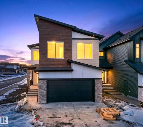 Contemporary home with stone siding, an attached garage, board and batten siding, and driveway - 8924 Mayday Way, Edmonton, AB 