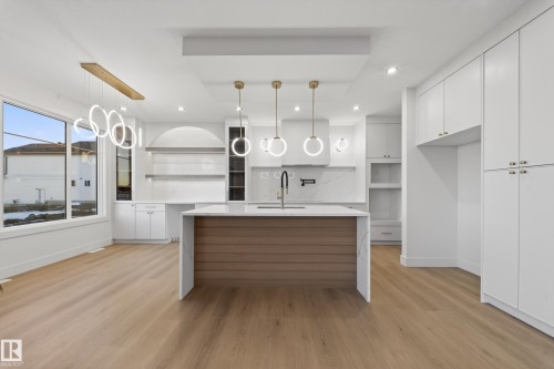 Kitchen featuring open shelves, white cabinets, decorative light fixtures, light stone countertops, and light wood-type flooring - 8924 Mayday Way, Edmonton, AB 
