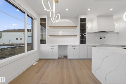 Kitchen featuring white cabinetry, light wood finished floors, light stone counters, open shelves, and glass fronted cabinets - 8924 Mayday Way, Edmonton, AB 