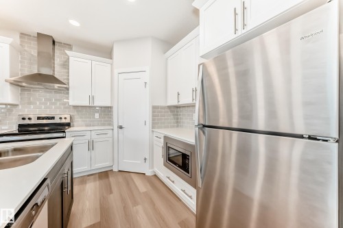 Kitchen featuring stainless steel appliances, light wood-style flooring, recessed lighting, light stone counters, and dual tone cabinets - 17926 62A Street, Edmonton, AB - Indoor Photo Showing Kitchen With Double Sink With Upgraded Kitchen