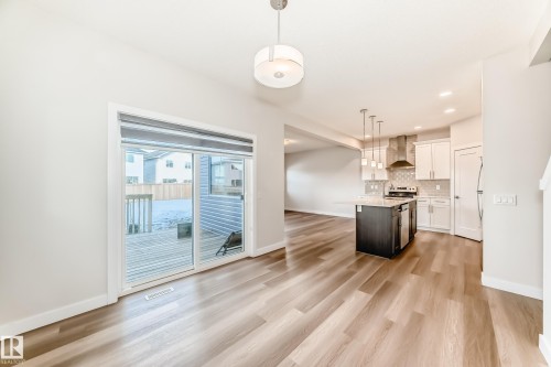 Two tone kitchen featuring a center island, pendant lighting, dual tone cabinets, light wood-style flooring, and tasteful backsplash - 17926 62A Street, Edmonton, AB - Indoor Photo Showing Kitchen