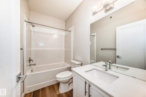 Bathroom featuring vanity, a textured ceiling,  shower combination, and dark wood finished floors - 17926 62A Street, Edmonton, AB - Indoor Photo Showing Bathroom