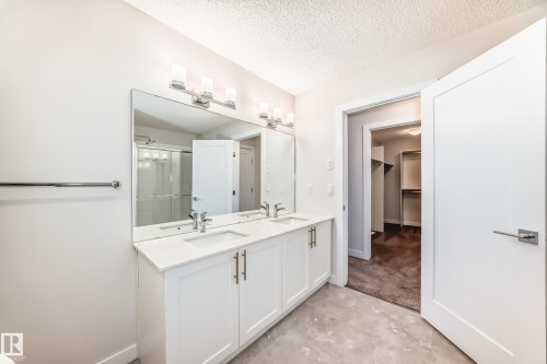 Bathroom with a stall shower, double vanity, a spacious closet, a textured ceiling, and unfinished concrete flooring - 17926 62A Street, Edmonton, AB - Indoor