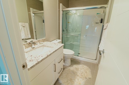 Full bath featuring vanity, a shower stall, and light tile patterned flooring - 301 625 Leger Way Nw, Edmonton, AB - Indoor Photo Showing Bathroom