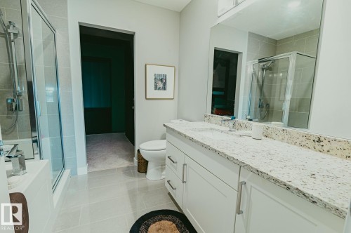 Full bathroom featuring vanity, a stall shower, and light tile patterned floors - 301 625 Leger Way Nw, Edmonton, AB - Indoor Photo Showing Bathroom