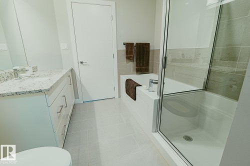 Full bathroom with vanity, a bath, light tile patterned flooring, and a stall shower - 301 625 Leger Way Nw, Edmonton, AB - Indoor Photo Showing Bathroom