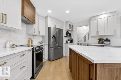 Kitchen featuring two tone cabinets, stainless steel appliances, light wood-style floors, light stone countertops, and open shelves - 