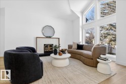Living room with light wood-style flooring, a tiled fireplace, and a high ceiling - 