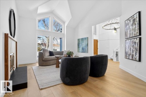 Living area featuring light wood finished floors, a fireplace with flush hearth, vaulted ceiling, and a chandelier - 218 Omand Drive, Edmonton, AB 