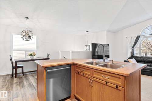 Kitchen with open floor plan, suspended lighting, light countertops, stainless steel dishwasher, and a center island with sink - 3015 49, Beaumont, AB - Indoor Photo Showing Kitchen With Double Sink