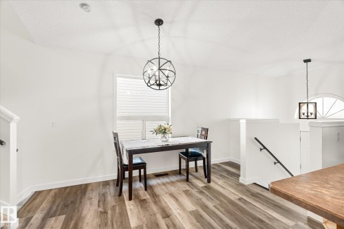 Dining area with suspended lighting, light wood-type flooring, and a textured ceiling - 3015 49, Beaumont, AB - Indoor Photo Showing Dining Room