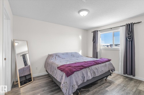 Bedroom featuring wood finished floors and a textured ceiling - 3015 49, Beaumont, AB - Indoor Photo Showing Bedroom
