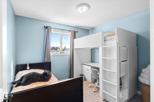 Bedroom with an office area, light wood-style floors, and a textured ceiling - 3015 49, Beaumont, AB - Indoor Photo Showing Bedroom