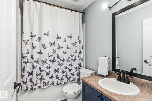 Full bath with a textured ceiling, vanity, and shower / bath combo - 3015 49, Beaumont, AB - Indoor Photo Showing Bathroom