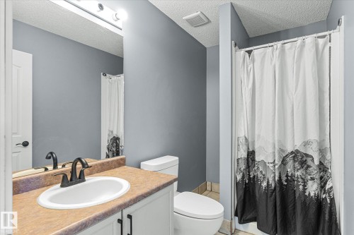 Full bath with a shower with curtain, vanity, and a textured ceiling - 3015 49, Beaumont, AB - Indoor Photo Showing Bathroom