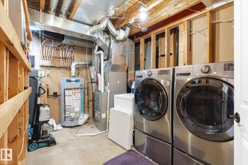 Laundry area featuring concrete flooring, gas water heater, washer and clothes dryer, and heating unit - 3015 49, Beaumont, AB - Indoor Photo Showing Laundry Room