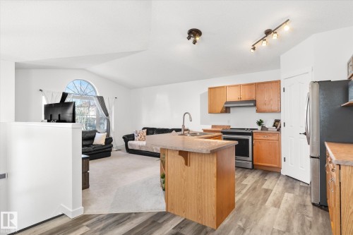 Kitchen with open floor plan, lofted ceiling, light countertops, stainless steel appliances, and a breakfast bar area - 3015 49, Beaumont, AB - Indoor Photo Showing Kitchen