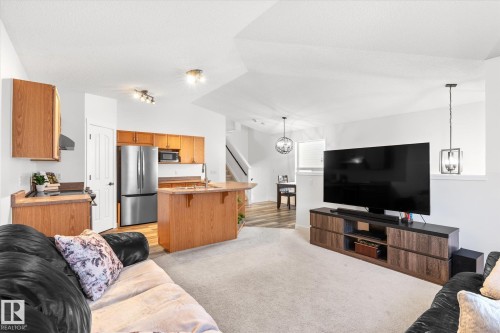 Living room with light colored carpet, suspended lighting, and vaulted ceiling - 3015 49, Beaumont, AB - Indoor