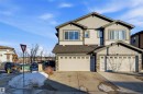 View of front of house with concrete driveway, stone siding, an attached garage, a residential view, and roof with shingles - 5003 Andison Close, Edmonton, AB  - Outdoor 
