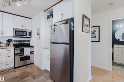 Kitchen with white cabinetry, stainless steel appliances, and light wood finished floors - 115 10545 Saskatchewan Drive, Edmonton, AB - Indoor Photo Showing Kitchen