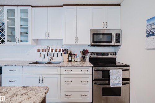Kitchen with stainless steel appliances, white cabinets, and glass insert cabinets - 115 10545 Saskatchewan Drive, Edmonton, AB - Indoor Photo Showing Kitchen