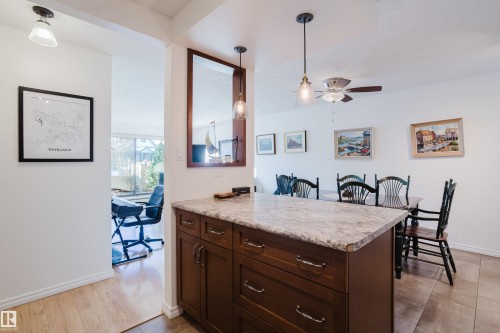 Kitchen featuring dark wood finish cabinetry, light countertops, hanging light fixtures, and ceiling fan - 115 10545 Saskatchewan Drive, Edmonton, AB - Indoor