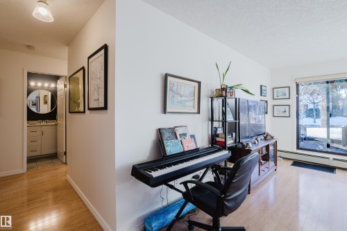 Office space with light wood-style floors, a textured ceiling, and a baseboard radiator - 115 10545 Saskatchewan Drive, Edmonton, AB - Indoor Photo Showing Other Room