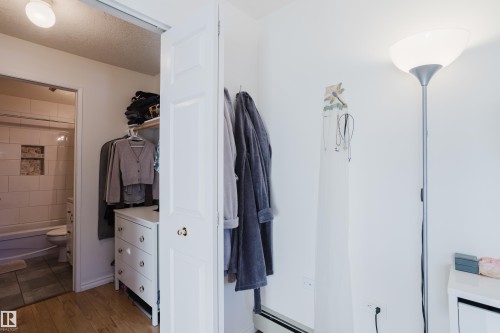 Bathroom with tub / shower combination, a textured ceiling, light wood-type flooring, and a baseboard heating unit - 115 10545 Saskatchewan Drive, Edmonton, AB - Indoor Photo Showing Other Room
