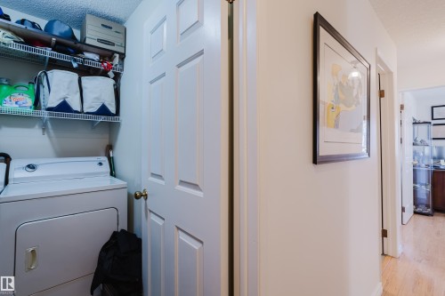 Laundry area featuring washer / dryer, a textured ceiling, and light wood finished floors - 115 10545 Saskatchewan Drive, Edmonton, AB - Indoor Photo Showing Laundry Room