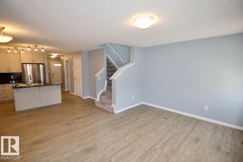 Kitchen featuring open floor plan, stainless steel fridge, a textured ceiling, a center island with sink, and tasteful backsplash - Upper 516 Ebbers Way, Edmonton, AB - Indoor Photo Showing Kitchen