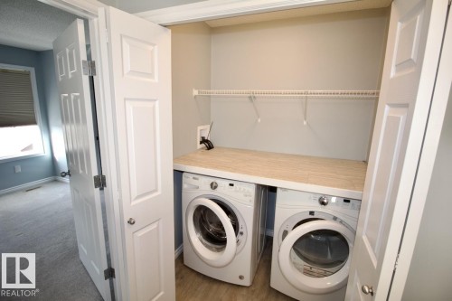 Laundry area featuring washer and dryer, a textured ceiling, and light carpet - Upper 516 Ebbers Way, Edmonton, AB - Indoor Photo Showing Laundry Room