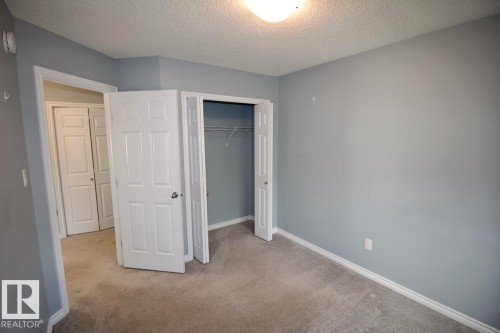 Unfurnished bedroom featuring a textured ceiling, light colored carpet, and a closet - Upper 516 Ebbers Way, Edmonton, AB - Indoor Photo Showing Other Room