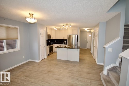 Kitchen featuring dark countertops, stainless steel appliances, tasteful backsplash, a textured ceiling, and open floor plan - Upper 516 Ebbers Way, Edmonton, AB - Indoor Photo Showing Kitchen With Double Sink