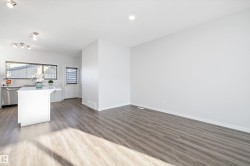 Kitchen with stainless steel dishwasher, light wood finished floors, open floor plan, a kitchen island, and white cabinetry - 
