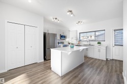 Kitchen featuring stainless steel appliances, a kitchen island, a textured ceiling, a kitchen bar, and light wood-style floors - 