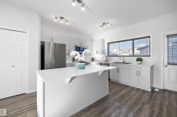 Kitchen featuring appliances with stainless steel finishes, a textured ceiling, a breakfast bar area, a kitchen island, and dark wood-style flooring - 