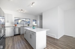 Kitchen featuring a center island, stainless steel appliances, a textured ceiling, dark wood finished floors, and white cabinets - 