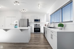 Kitchen with appliances with stainless steel finishes, dark wood-type flooring, white cabinets, a breakfast bar, and a textured ceiling - 