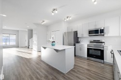 Kitchen featuring stainless steel appliances, light wood-style floors, white cabinets, a kitchen island, and recessed lighting - 