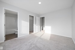 Unfurnished bedroom with a walk in closet, carpet flooring, and ensuite bathroom - 