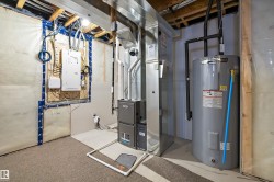 Utilities featuring water heater, electric panel, and heating unit - 