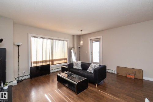 Living room with dark wood finished floors and a baseboard heating unit - 2005 10136 104 Street, Edmonton, AB - Indoor Photo Showing Living Room