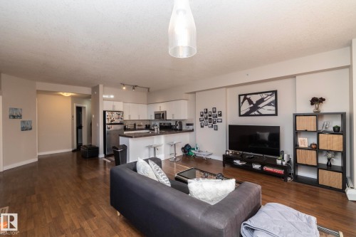 Living room featuring dark wood-type flooring, a textured ceiling, and rail lighting - 2005 10136 104 Street, Edmonton, AB - Indoor Photo Showing Living Room