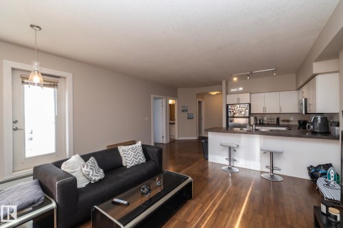 Living room featuring dark wood-type flooring and a baseboard heating unit - 2005 10136 104 Street, Edmonton, AB - Indoor