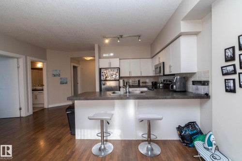 Kitchen featuring a peninsula, stainless steel appliances, white cabinetry, a kitchen breakfast bar, and backsplash - 2005 10136 104 Street, Edmonton, AB - Indoor Photo Showing Kitchen
