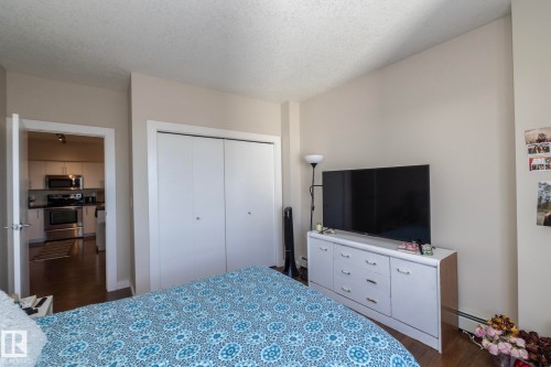 Bedroom with dark wood finished floors, a textured ceiling, a closet, and baseboard heating - 2005 10136 104 Street, Edmonton, AB - Indoor Photo Showing Bedroom