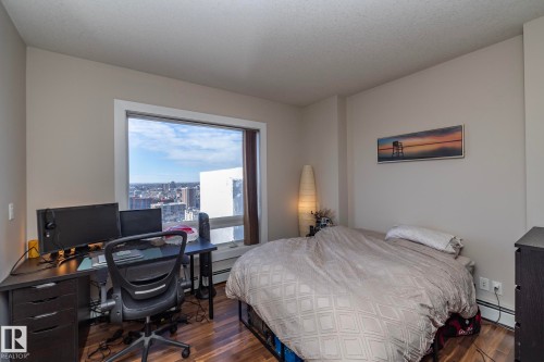 Bedroom with an office area, hardwood / wood-style floors, and a baseboard heating unit - 2005 10136 104 Street, Edmonton, AB - Indoor Photo Showing Bedroom