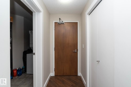 Corridor featuring a textured ceiling, stacked washer and dryer, and dark wood-style floors - 2005 10136 104 Street, Edmonton, AB - Indoor Photo Showing Other Room