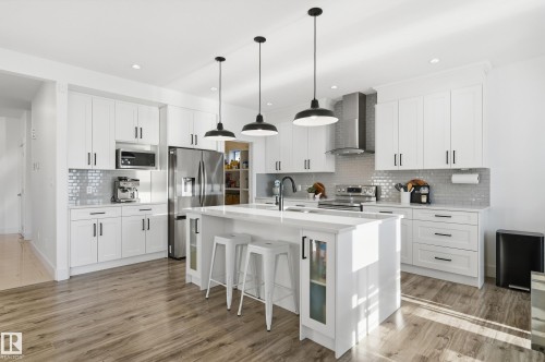 Kitchen featuring decorative light fixtures, stainless steel appliances, a kitchen breakfast bar, white cabinets, and a kitchen island with sink - 30 Willow Link, Fort Saskatchewan, AB - Indoor Photo Showing Kitchen With Upgraded Kitchen