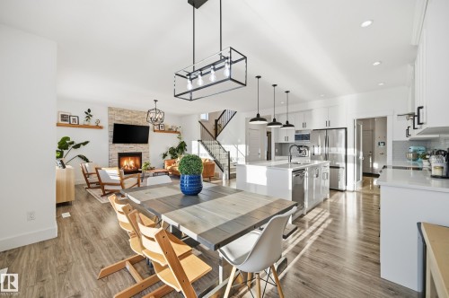 Dining room with light wood-type flooring, a stone fireplace, and hanging lights - 30 Willow Link, Fort Saskatchewan, AB - Indoor Photo Showing Dining Room